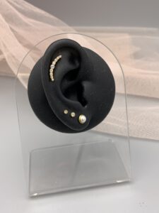 Modellohr mit Helix-Piercing und klassischen Ohrringen