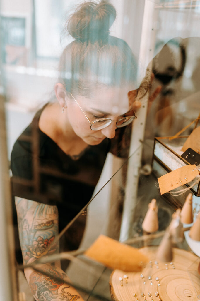 Mitarbeiterin im Piercing-shop in Bottrop sortiert Schmuck in einer Vitrine